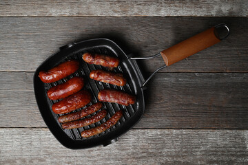 Delicious homemade hot grilled sausage in a black pan on a wooden background