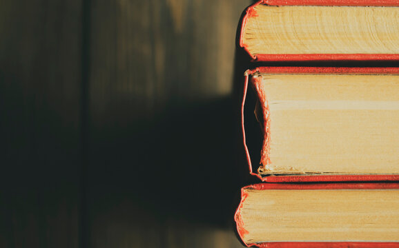 Macro Photography Of The Spine Of The Book. Spine Of Books With Scarlet Covers On A Wooden Background. Stubs Of The Book. Three Books With Stubs.