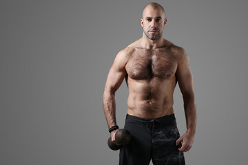 Fototapeta na wymiar Sporty muscular bodybuilder posing with dumbbells on a dark background