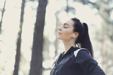 Young beautiful brunette woman enjoying music in headphones in nature