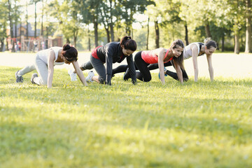 A group of healthy, beautiful, athletic women doing sports exercises in the park.