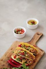 Fresh Mexican tacos with meat and vegetable fillings on a wooden cutting board