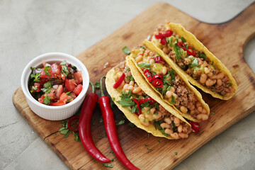 Fresh Mexican tacos with meat and vegetable fillings on a wooden cutting board
