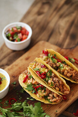 Close view of fresh Mexican tacos with meat and vegetable fillings on a wooden cutting board