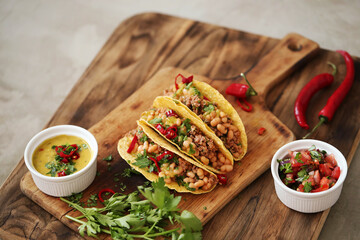 Close view of fresh Mexican tacos with meat and vegetable fillings on a wooden cutting board