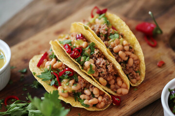 Close view of fresh Mexican tacos with meat and vegetable fillings on a wooden cutting board