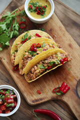 Close view of fresh Mexican tacos with meat and vegetable fillings on a wooden cutting board