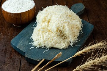Dough made from thin strands of kataifi before cooking, wooden table, wooden board.