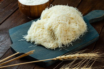 Kataifi dough on a wooden board and on a wooden table.