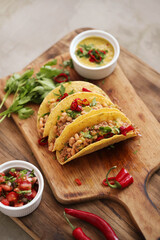 Traditional Mexican tacos with meat and vegetables on a wooden cutting board