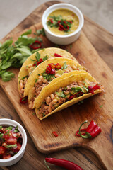 Traditional Mexican tacos with meat and vegetables on a wooden cutting board