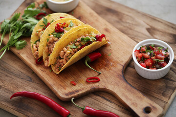 Traditional Mexican tacos with meat and vegetables on a wooden cutting board