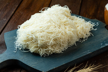 Kataifi dough on a wooden board, raw thin strand dough.
