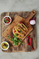 Traditional Mexican tacos with meat and vegetables on a wooden cutting board