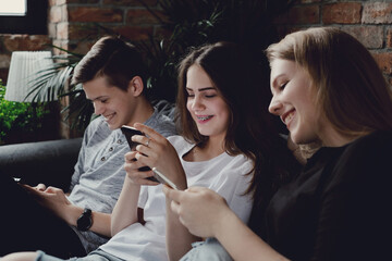 Teenagers have fun with smartphones on the couch at home