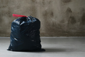 The big black garbage bag placed on the floor.