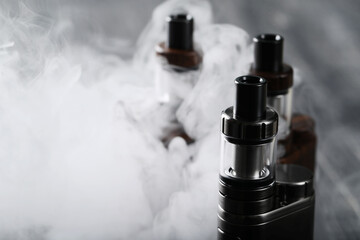 Close view of vaping device with mist on a wooden dark background
