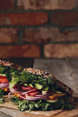 Two fresh, tasty vegetable sandwiches wrapped in paper on a wooden cutting board
