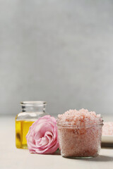 Obraz na płótnie Canvas A glass jar of pink sea salt with oil and flower for cosmetologic procedures