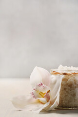A glass jar of pink sea salt with flower for cosmetologic procedures