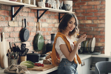 Young, beautiful, charming woman eating delicious yogurt in the kitchen at home