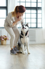 Beautiful, young woman playing with her dog Husky at home