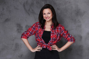 Photo of smiling , adorable , brunette woman posing with hands on her hips isolated on dark color background