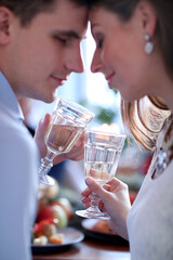 Young couple touching heads and holding glasses of champagne 