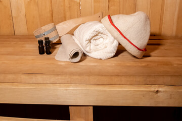 Fototapeta na wymiar Traditional old Russian bathhouse SPA Concept. Interior details Finnish sauna steam room with traditional sauna accessories set basin towel aroma oil scoop felt. Relax country village bath concept
