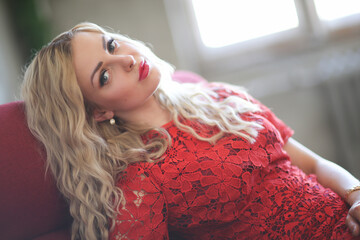 A young, beautiful woman with wavy hair in a red dress posing at the camera