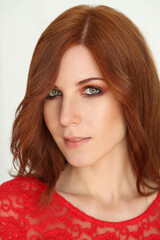 Naklejka premium Close-up photo of a beautiful redheaded woman in a red lace dress looking at the camera