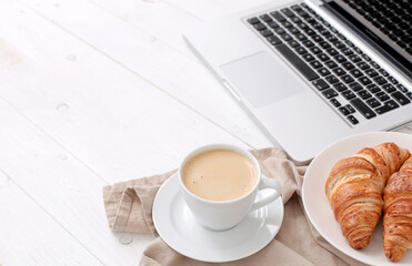 A cup of aroma coffee with croissants and computer on a marble background