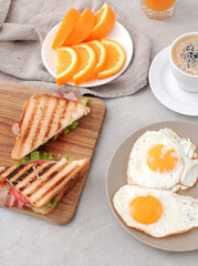 Top view of morning breakfast with fried eggs,sandwiches and a cup of coffee on a marble background