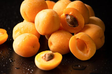 A handful of ripe raw apricots on a dark background