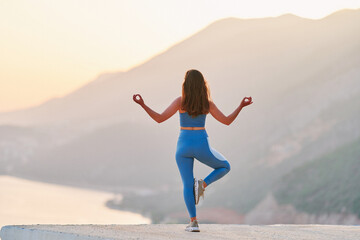 Inspired female enjoying of meditation on top with beautiful view at sunset time. Relief stress and clean healthy minds