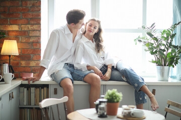 Photosession of beautiful,young couple lying and hugging on the windowsill in the kitchen room