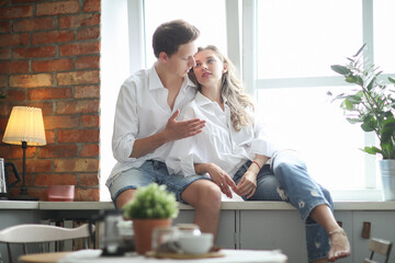 Photosession of beautiful,young couple lying and hugging on the windowsill in the kitchen room