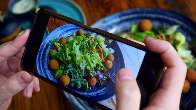 The blogger takes a photo of his lunch on his smartphone to share it with his followers on social networks. Photographing food is a new trend in social networks. Healthy food is popularized.