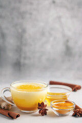 Golden Cinnamon Turmeric Milk. Golden milk with species turmeric, cinnamon, honey and ginger on grey background. Trendy hot Healthy drink . Indian Garam Doodh.