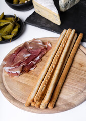 Image of delicious snacks with bacon and breadsticks isolated on a wooden cutting board.