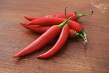 Fresh juicy red hot chili peppers isolated on a wooden background.