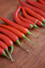 Fresh juicy red hot chili peppers isolated on a wooden background.