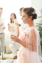 Woman in pink dress holding a glass of champagne at a party.