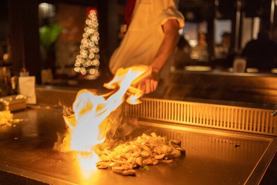 Professional cook frying chopped onion on the hibachi