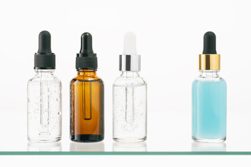 Several mockup assorted glass bottles on glass shelf. cosmetics collagen serum,organic essential or aroma oil for beauty skin care on white background