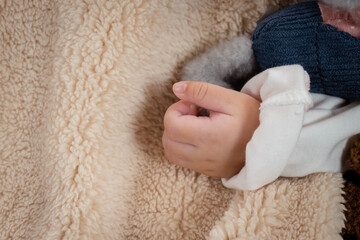 Close-up photo of a small hand of a 3-month-old Asian newborn baby girl's left hand sleep on a soft bed In the bedroom looks relaxed.