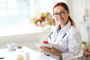 Woman-doctor sitting and working with medication history record forms in hospital or clinic