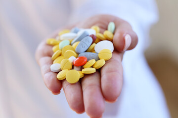 Many tablets of various medicinal drugs in the hand