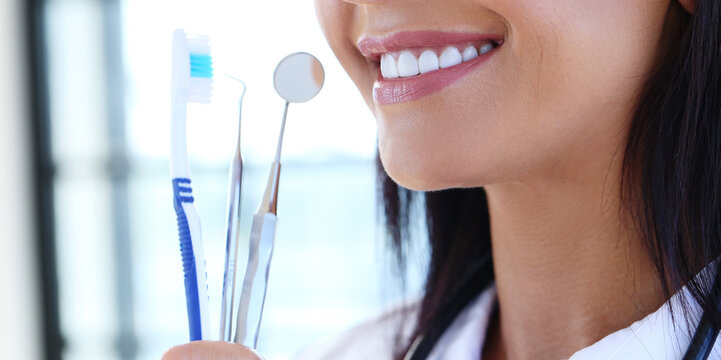Confident, professional female-dentist shows how to properly care for your teeth