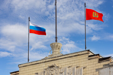 Flags of Russia and Krasnoyarsk Territory on the roof of the office building against the blue sky. For a political background. Translation: RSFSR.